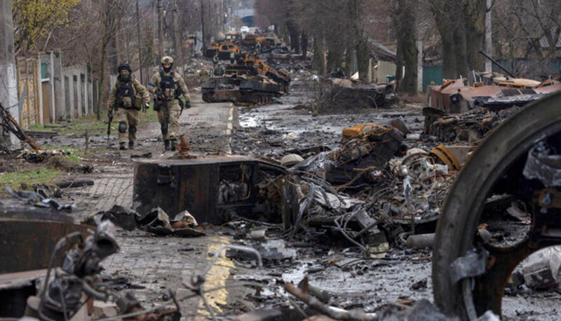Soldiers walk amid destroyed Russian tanks in Bucha, in the outskirts of Kyiv, Ukraine, Sunday, April 3, 2022.