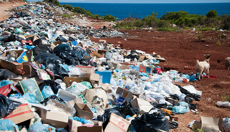 A mountain of trash against a blue ocean.