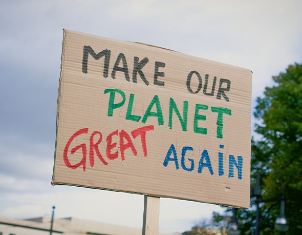 A cardboard sign reading, "Make our planet great again."
