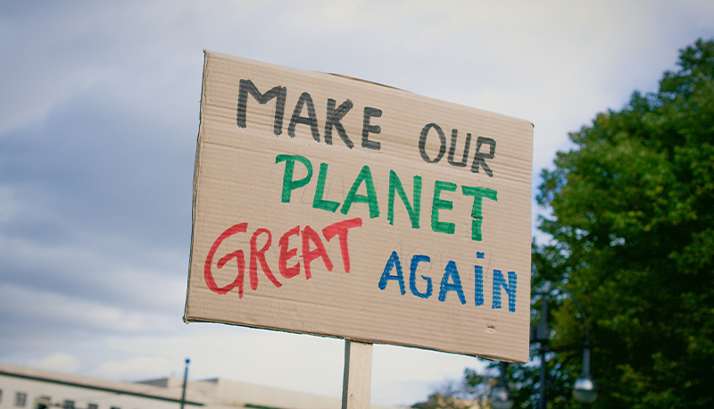 A cardboard sign reading, "Make our planet great again."