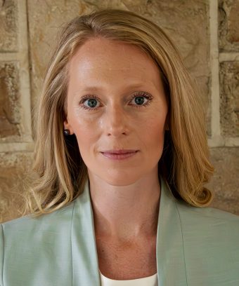Headshot photo of Sarah Bidgood, a white woman with blonde hair wearing a teal blazer