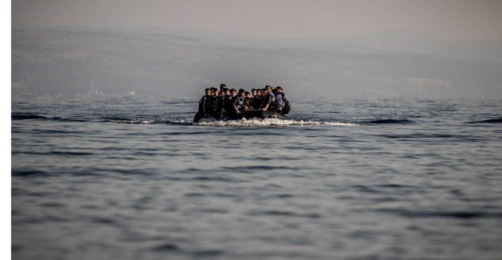 A group of migrants sit atop a small boat on the open ocean