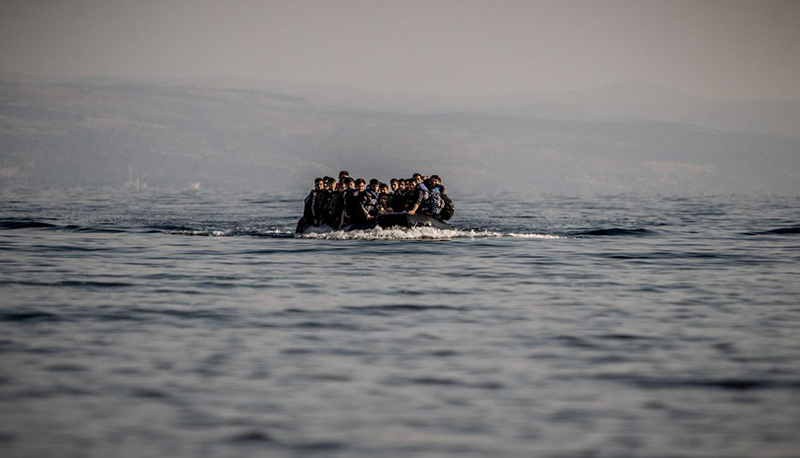 A group of migrants sit atop a small boat on the open ocean