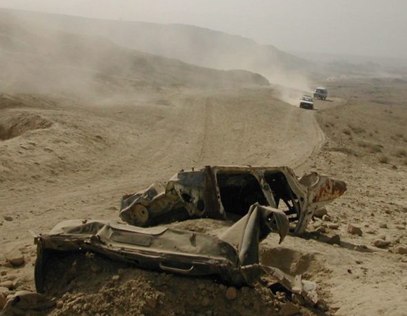 Remnants of a damaged vehicle lie next to a dry dirt road in Kabul