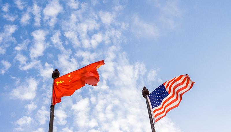 The Chinese and the United States flags flying against a blue sky