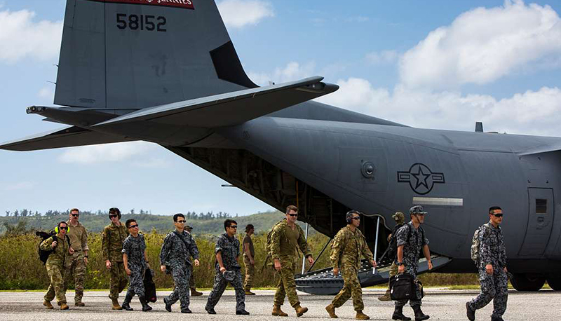 Royal Australian Air Force (RAAF), U.S. Air Force and Japanese Self-Defense Force (JASDF) personnel walk next to a military aircraft