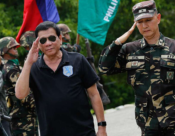 Philippines President Rodrigo Duterte salutes alongside soldiers upon arriving at a military base.