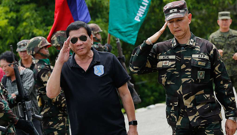 Philippines President Rodrigo Duterte salutes alongside soldiers upon arriving at a military base.