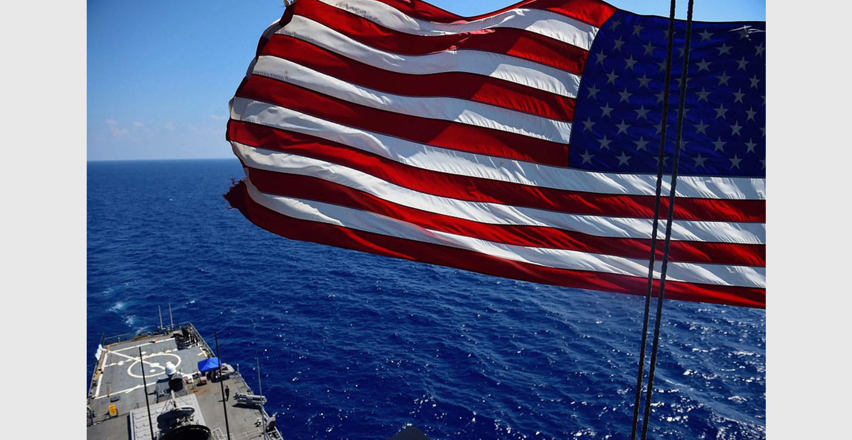 An American flag flies above a U.S. Navy ship at sea