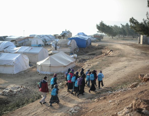 Photo of group of people walking through a dirt path.