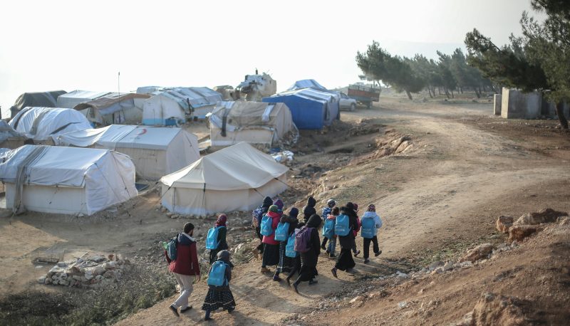 Photo of group of people walking through a dirt path.