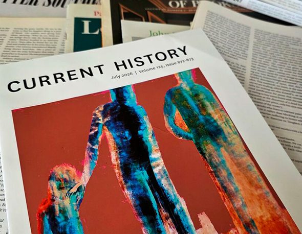 The cover of the July 2026 issue of Current History, photographed atop of a stack of other journals and newspaper articles.