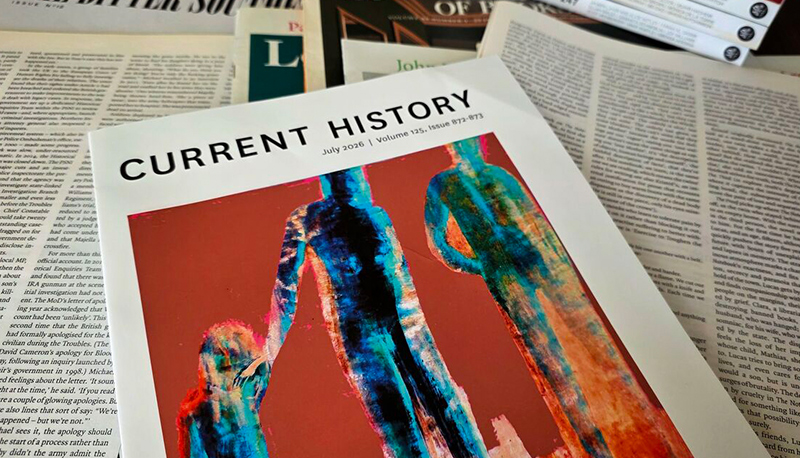 The cover of the July 2026 issue of Current History, photographed atop of a stack of other journals and newspaper articles.